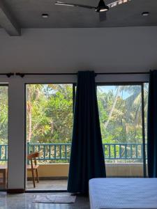 a bedroom with a bed and a large window at Cielo Hiriketiya in Hiriketiya