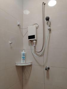 a shower in a bathroom with a hand dryer on the wall at Risfeena Home in Sekinchan