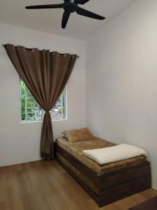 a bedroom with a bed with a ceiling fan at Risfeena Home in Sekinchan