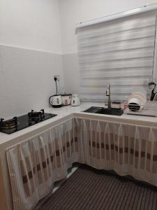 a kitchen counter with a sink and a window at Risfeena Home in Sekinchan