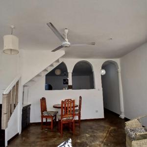 a living room with a ceiling fan and a table and chairs at Tatia apartment in Malindi +3 photos