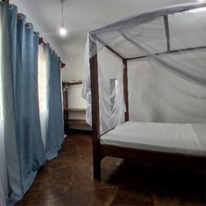 a bedroom with a canopy bed with blue curtains at Tatia apartment in Malindi