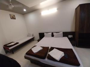 a bedroom with two beds and a bench in it at Hotel Jawahar Palace in Bhusāwal