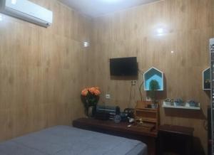 a bedroom with a wooden wall with a bed and a television at FM Homestay Banyuwangi in Banyuwangi