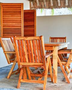 two wooden chairs and a wooden table with a table and chairs at Amani Beach House, Ushongo in Pangani +4 photos