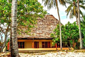 a house with palm trees in front of it at Amani Beach House, Ushongo in Pangani