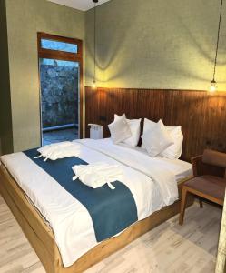 a bedroom with a large bed with white sheets and a chair at Valley Park Dilijan in Dilijan