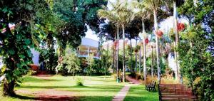 a park with benches and palm trees and a building at Greenyard Beach Hotel in Entebbe +12 photos