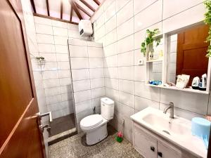 a white bathroom with a toilet and a sink at Lonovilla Menoreh Yogyakarta in Junggrangan