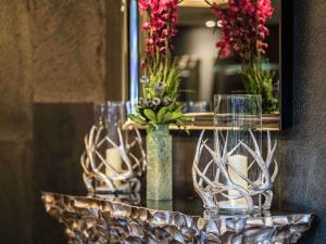 a table with glasses and flowers in a mirror at Novotel Orléans Saint Jean de Braye in Saint-Jean-de-Braye