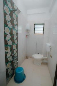 a white bathroom with a toilet and a window at Aashray Guestroom in Murud +8 photos