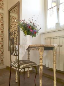 una mesa y una silla con un jarrón de flores en Spello House Dormio, en Spello