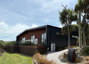 a house with a black facade and a palm tree at 45 degrees South in Kakanui