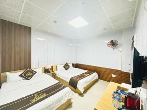 a hotel room with two beds and a flat screen tv at KHÁCH SẠN PHÚ HƯNG in Ho Chi Minh City