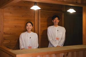 two people in white uniforms standing in a room at Travel Stop UNNOWA in Tomi