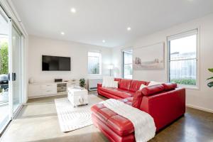 a living room with a red couch and a tv at Ocean Grove Beach House 2 - Pets - Late checkout - Accessible in Ocean Grove