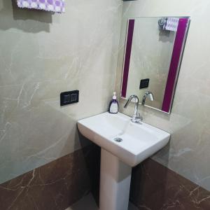 a bathroom with a white sink and a mirror at Golden Valley Abode in Siddapur