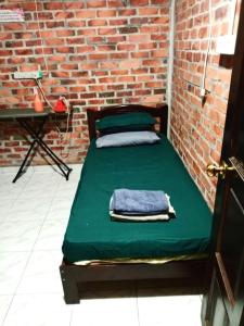 a bed in a room with a brick wall at Homestay Anjang in Tapah +2 photos