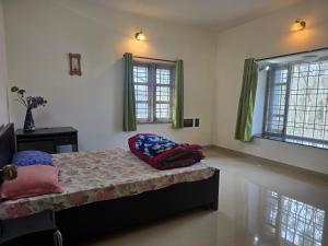 a bedroom with a bed and two windows at Guru Villa in Yercaud