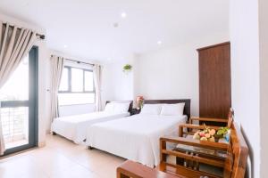 two beds in a white room with a window at Lotus Rock Hotel Đà Nẵng in Danang +10 photos