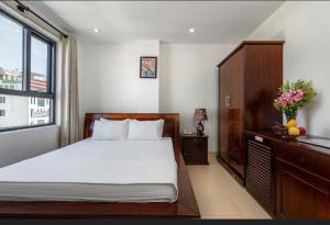 a bedroom with a bed and a dresser and a window at Lotus Rock Hotel Đà Nẵng in Danang