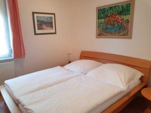 a white bed in a bedroom with a painting on the wall at Fewo 1 im Fischerhaus mit Wintergarten und Terrasse in Seedorf