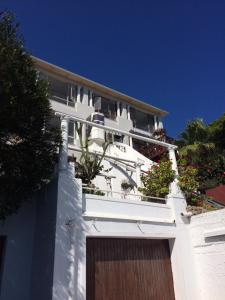 a white house with flowers on the balcony at The Cove in Fish hoek