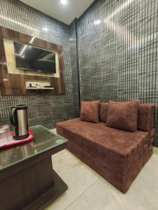 a brown couch in a room with a tv at Hotel Gulmohar in Haridwār