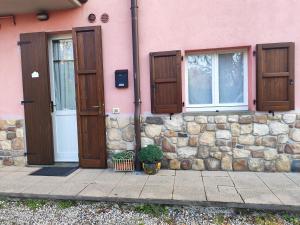 a pink building with wooden doors and a stone wall at Margherita in Seriate