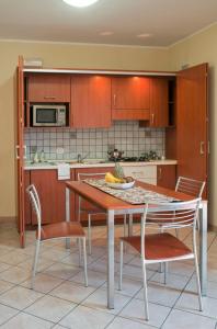 cocina con mesa, sillas y microondas en Motta Residence Hotel, en Motta SantʼAnastasia