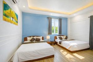 two beds in a room with blue walls at Thuận Phát Hotel in Soc Trang