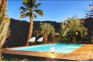 a swimming pool with two chairs and palm trees at プールサイドヴィラ館山 in Tateyama