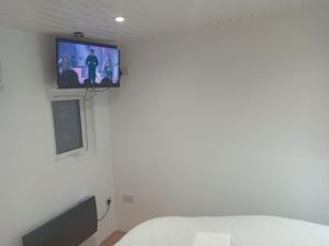 a bedroom with a tv on the wall and a bed at Lovely Timber Lodge Ensuite room in Corby Town centre NN17 in Rockingham