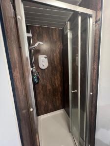 a shower with a glass door in a bathroom at Lovely Timber Lodge Ensuite room in Corby Town centre NN17 in Rockingham +3 photos