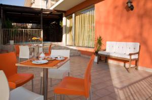 een patio met een houten tafel en stoelen en een tafel en een stoeltje bij Motta Residence Hotel in Motta SantʼAnastasia