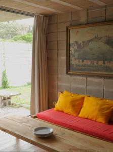1 cama con almohadas amarillas y rojas en una habitación en Galpon Miin, en La Pedrera