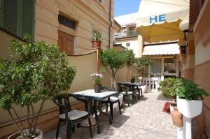 un patio extérieur avec des tables, des chaises et des arbres dans l'établissement Hotel Ely, à Viareggio