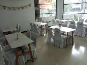 a restaurant with white tables and chairs and a window at tekMIRA Hotel in Bandung