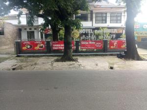 a building with a fence and two trees on a street at tekMIRA Hotel in Bandung
