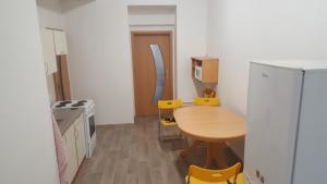 eine kleine Küche mit einem Holztisch und gelben Stühlen in der Unterkunft Apartmán u červeného kostela in Teplice