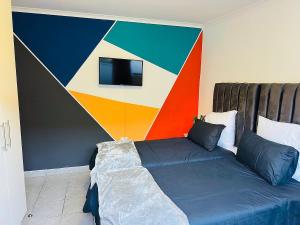 a bedroom with a bed with a colorful wall at AAA Luxury Cottages in Cape Town