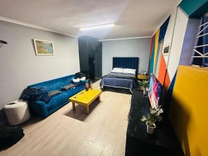 a living room with a blue couch and a bed at AAA Luxury Cottages in Cape Town
