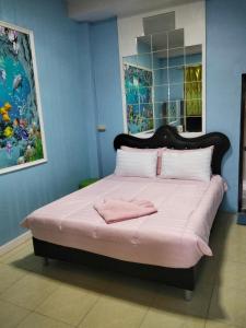 a bedroom with a large bed with pink sheets at บ้านพัก สายรุ้ง in Ban Hua Saphan