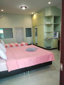 a bedroom with two beds with pink sheets and shelves at บ้านพัก สายรุ้ง in Ban Hua Saphan