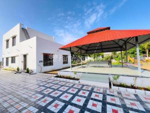 a villa with a swimming pool and a red roof at Grey Stone Farm House in Surat