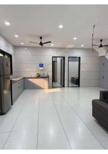 a kitchen and living room with a white tile floor at Grey Stone Farm House in Surat