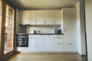 a kitchen with white cabinets and a sink at Appartement cocooning à Charmey in Charmey +9 photos