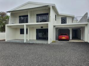 a white house with a red car parked in front of it at Jannat Residence in Curepipe