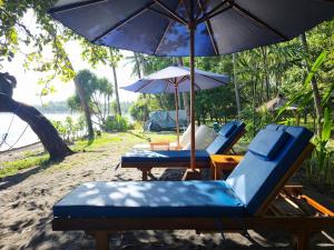 a group of chairs and an umbrella on the beach at Secret Beach Beachfront Villa in Papak