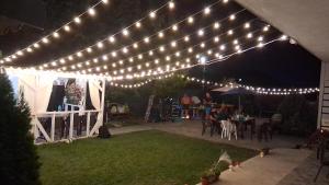 a pergola with lights on a backyard at night at Vila B&P in Costinesti